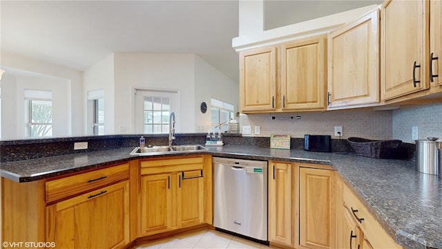 kitchen with dishwasher, a sink, a peninsula, dark stone countertops, and tasteful backsplash