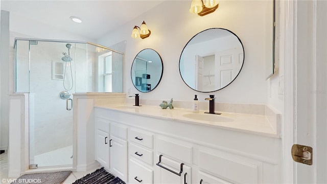 bathroom with a shower stall, tile patterned floors, double vanity, and a sink