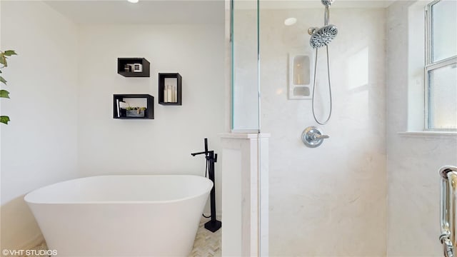 bathroom featuring walk in shower and a freestanding tub