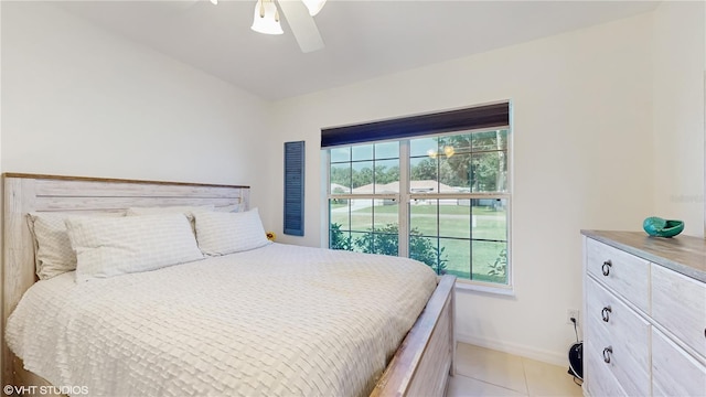 bedroom featuring baseboards, light tile patterned floors, and a ceiling fan