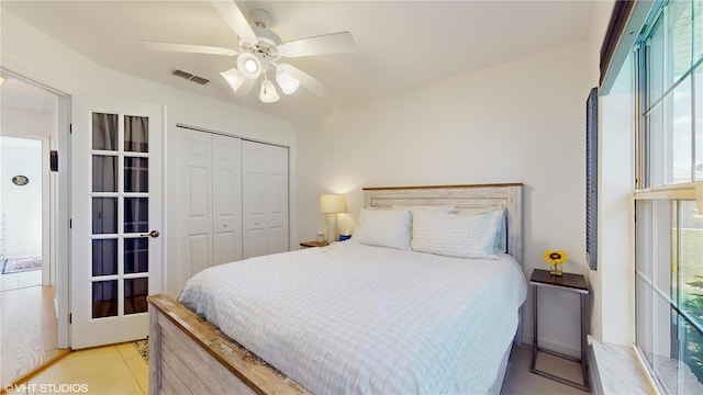 bedroom featuring a closet, light tile patterned floors, visible vents, and a ceiling fan