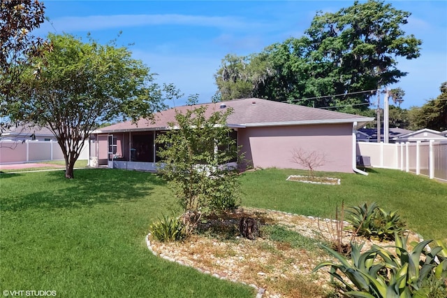 view of front of home with a fenced backyard, a sunroom, and a front lawn