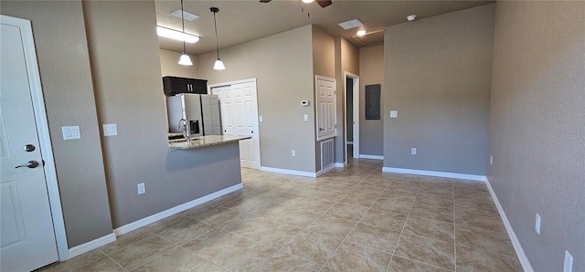 kitchen featuring a ceiling fan, light stone counters, visible vents, stainless steel fridge, and electric panel