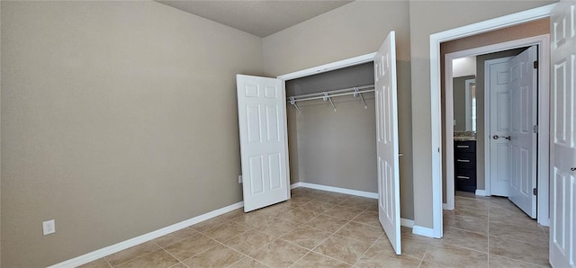 unfurnished bedroom with light tile patterned flooring, a closet, and baseboards