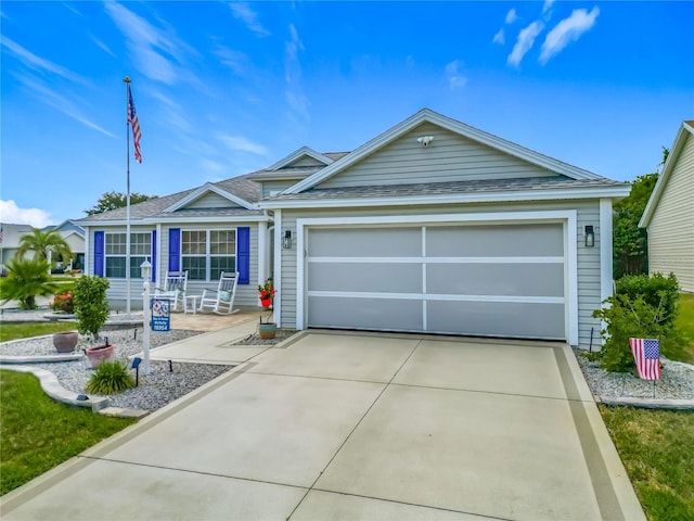 ranch-style house with covered porch, roof with shingles, concrete driveway, and a garage