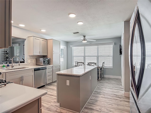 kitchen with a ceiling fan, light countertops, appliances with stainless steel finishes, and a center island