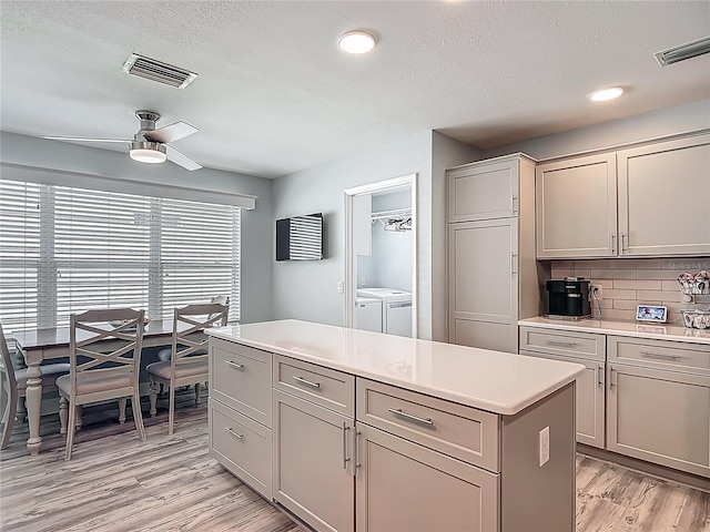 kitchen featuring separate washer and dryer, a ceiling fan, visible vents, and light wood-style floors