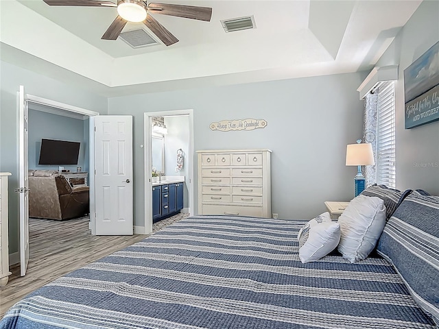 bedroom featuring a raised ceiling, light wood finished floors, and visible vents