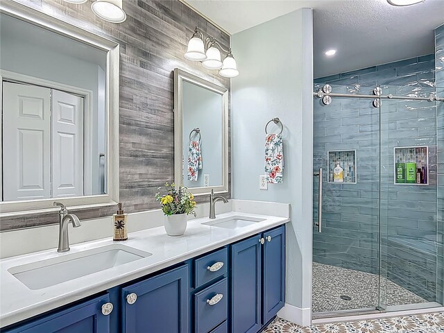 full bath featuring double vanity, a stall shower, and a sink