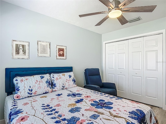 bedroom featuring ceiling fan, a closet, visible vents, and wood finished floors