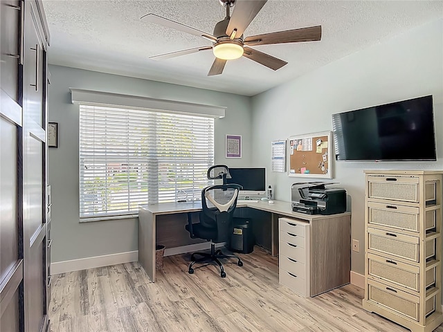 office with a ceiling fan, baseboards, light wood-style flooring, and a textured ceiling