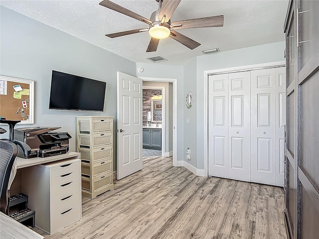 home office with light wood-type flooring, visible vents, baseboards, and ceiling fan