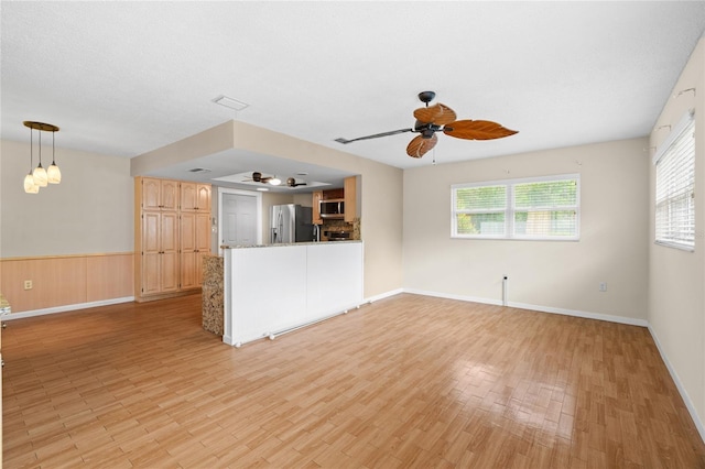 8130 SW 209th Court Rd, Dunnellon, FL 34431 - unfurnished living room with ceiling fan, light wood-type flooring, a wainscoted wall, and baseboards
