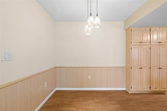 8130 SW 209th Court Rd, Dunnellon, FL 34431 - unfurnished dining area featuring a wainscoted wall, a chandelier, light wood-type flooring, and a textured ceiling