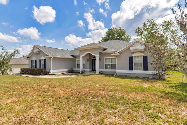 ranch-style home with a shingled roof, stucco siding, and a front yard