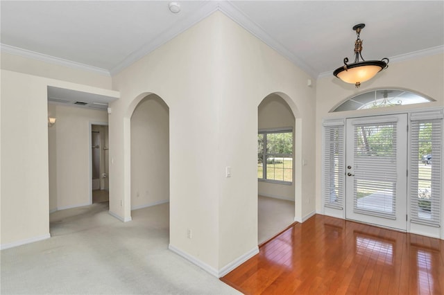 entryway with arched walkways, baseboards, visible vents, ornamental molding, and hardwood / wood-style flooring