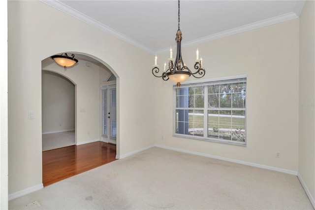 spare room featuring carpet floors, arched walkways, a chandelier, and ornamental molding