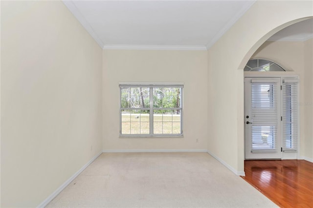 carpeted entryway with baseboards, arched walkways, and ornamental molding