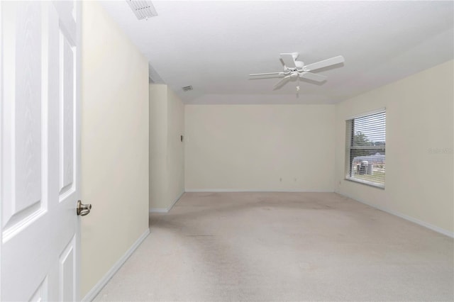empty room with light colored carpet, a ceiling fan, baseboards, and visible vents