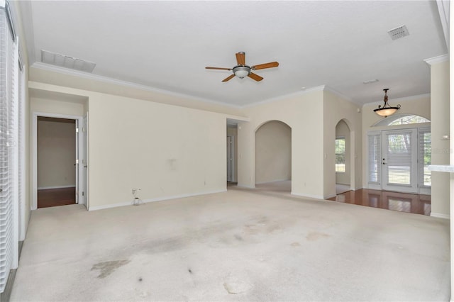 unfurnished living room with crown molding, arched walkways, light colored carpet, and visible vents