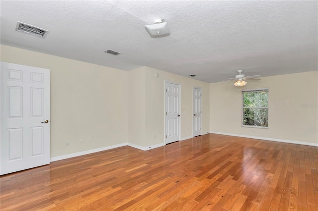 spare room with ceiling fan, light wood finished floors, a textured ceiling, and visible vents