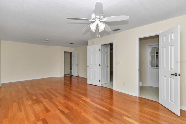 spare room featuring visible vents, baseboards, a textured ceiling, a ceiling fan, and light wood finished floors