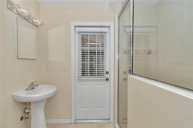bathroom with baseboards and a tile shower