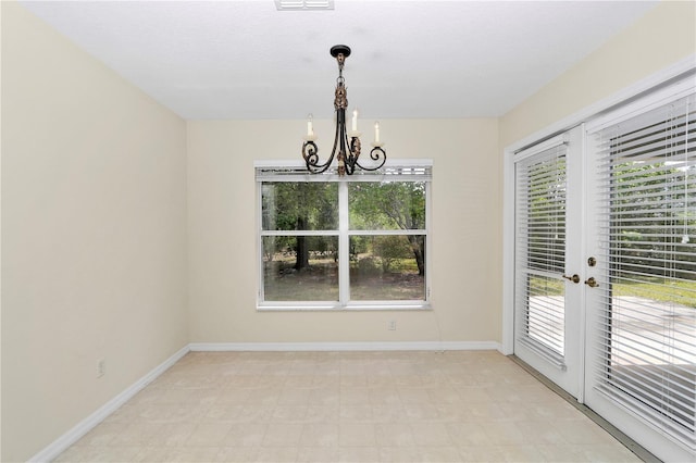 unfurnished dining area featuring baseboards, visible vents, and a notable chandelier