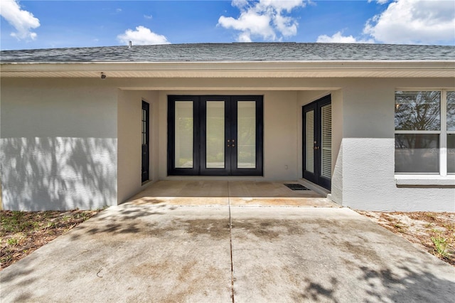 doorway to property featuring roof with shingles, stucco siding, and french doors