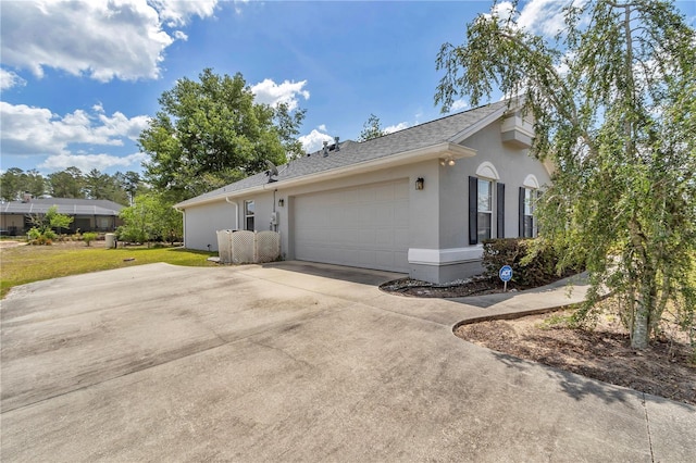 view of home's exterior featuring roof with shingles, a lawn, a garage, concrete driveway, and stucco siding
