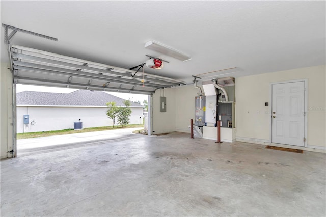 garage featuring heating unit, a garage door opener, gas water heater, and electric panel