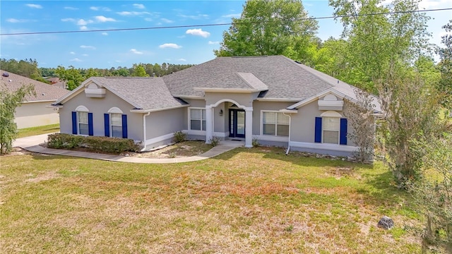 ranch-style home with a shingled roof, a front yard, and stucco siding