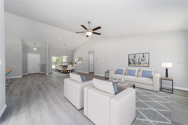 living room with ceiling fan, wood finished floors, vaulted ceiling, and baseboards