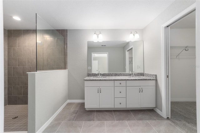 full bath featuring double vanity, walk in shower, tile patterned flooring, and a walk in closet