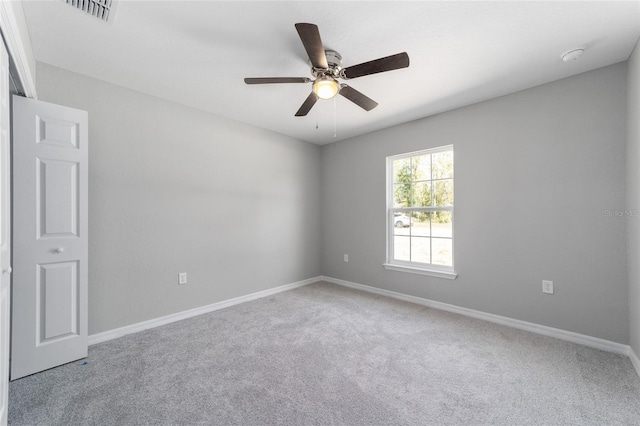 carpeted spare room featuring ceiling fan and baseboards