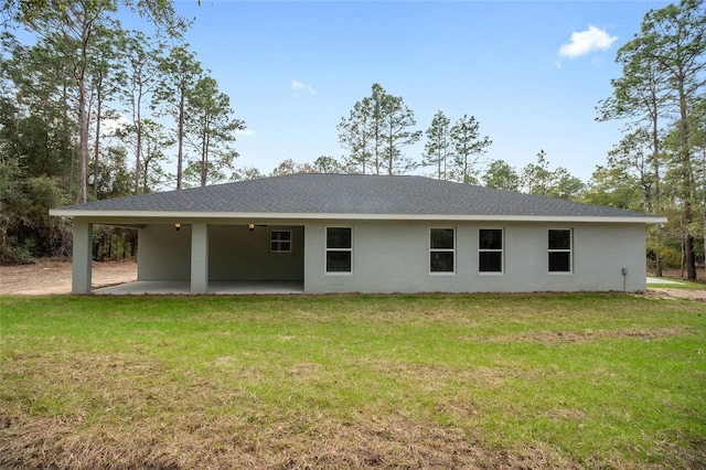 rear view of property featuring stucco siding, a patio area, an attached carport, and a lawn