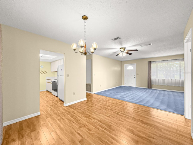 6263 SW 107th St, Ocala, FL 34476 - empty room with a textured ceiling, ceiling fan with notable chandelier, light wood-type flooring, and visible vents