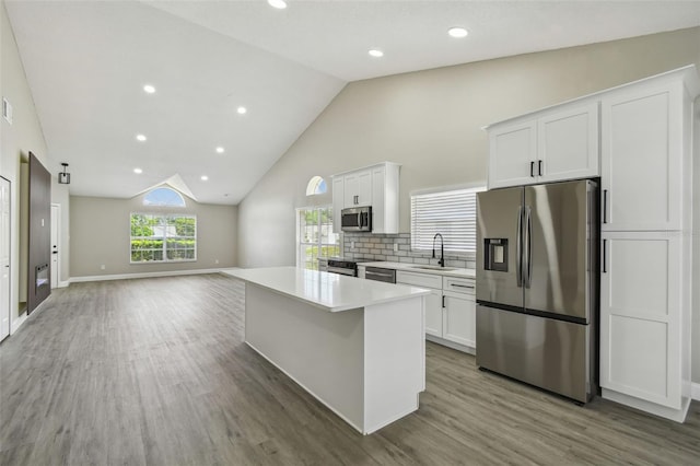 1317 Ravida Woods Dr, Apopka, FL 32703 - kitchen with stainless steel appliances, a sink, wood finished floors, white cabinets, and a kitchen island