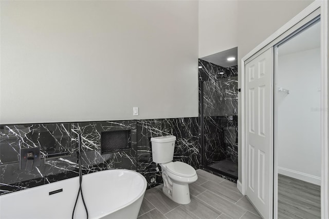 1317 Ravida Woods Dr, Apopka, FL 32703 - bathroom with toilet, a marble finish shower, a freestanding tub, tile walls, and a wainscoted wall