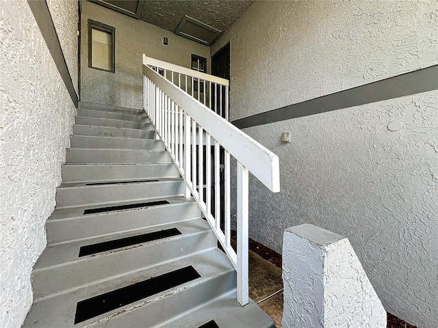 stairway featuring a textured wall