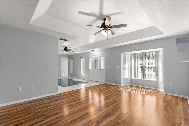 6758 SW 114th Street Rd, Ocala, FL 34476 - unfurnished living room with a textured ceiling, a ceiling fan, a raised ceiling, and light wood-style floors