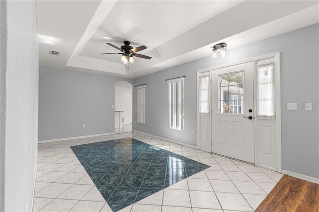6758 SW 114th Street Rd, Ocala, FL 34476 - foyer entrance with a tray ceiling, light tile patterned floors, baseboards, visible vents, and arched walkways