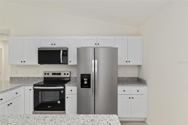 23131 SW Rainelle Rd, Dunnellon, FL 34431 - kitchen featuring stainless steel appliances, vaulted ceiling, white cabinetry, and light stone countertops