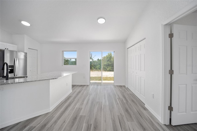 23131 SW Rainelle Rd, Dunnellon, FL 34431 - kitchen with stainless steel refrigerator with ice dispenser, light wood-style flooring, light stone countertops, white cabinetry, and baseboards