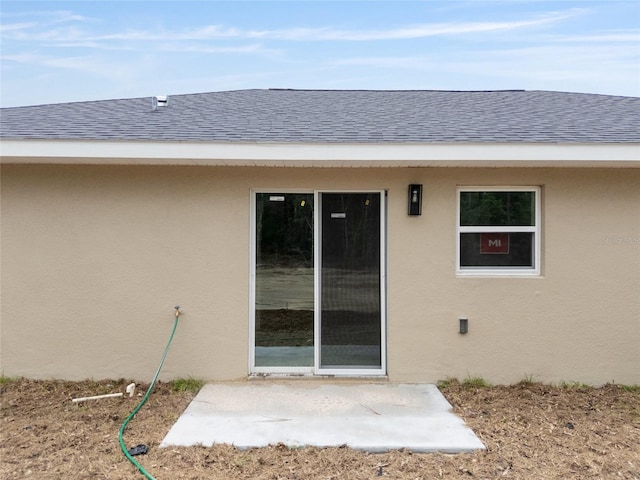 23131 SW Rainelle Rd, Dunnellon, FL 34431 - property entrance featuring stucco siding, a patio area, and a shingled roof