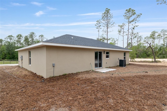 23131 SW Rainelle Rd, Dunnellon, FL 34431 - rear view of house featuring central AC, stucco siding, roof with shingles, and fence