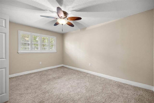 carpeted empty room featuring ceiling fan and baseboards