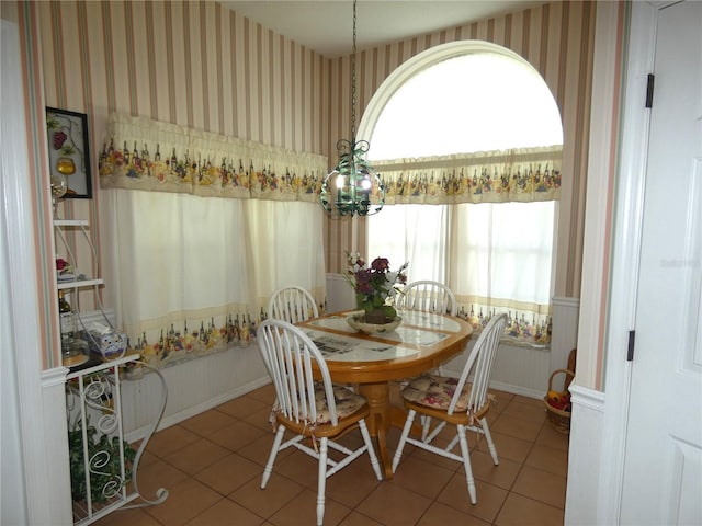 tiled dining area with a chandelier, baseboards, and wallpapered walls