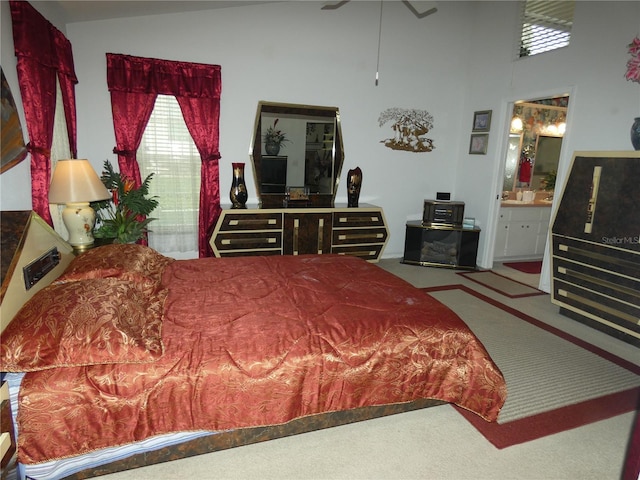 bedroom featuring ensuite bathroom, carpet floors, and high vaulted ceiling