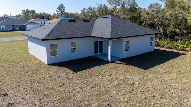 back of property with roof with shingles, a patio area, stucco siding, and a lawn